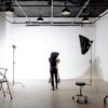 Back view of unrecognizable professional photographer taking photo of anonymous model in modern light studio