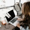 Close-up Photography of Woman Sitting Beside Table While Using Macbook